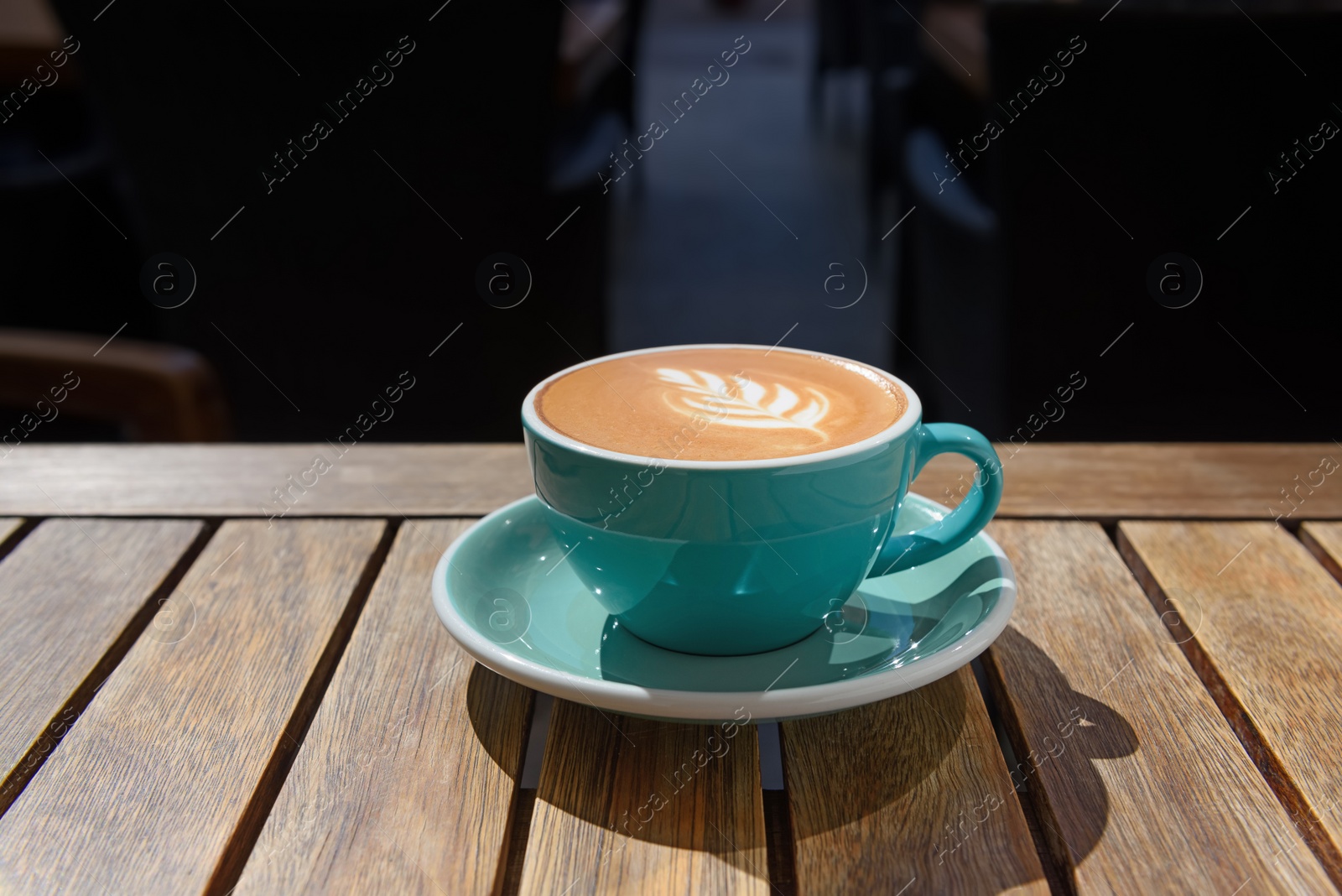 Photo of Cup of aromatic hot coffee on wooden table in outdoor cafe