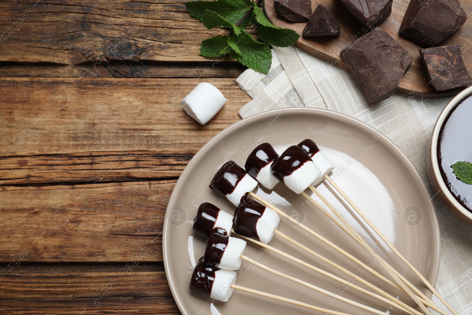 Photo of Delicious marshmallows covered with chocolate on wooden table, flat lay