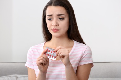 Photo of Beautiful young woman with pills at home