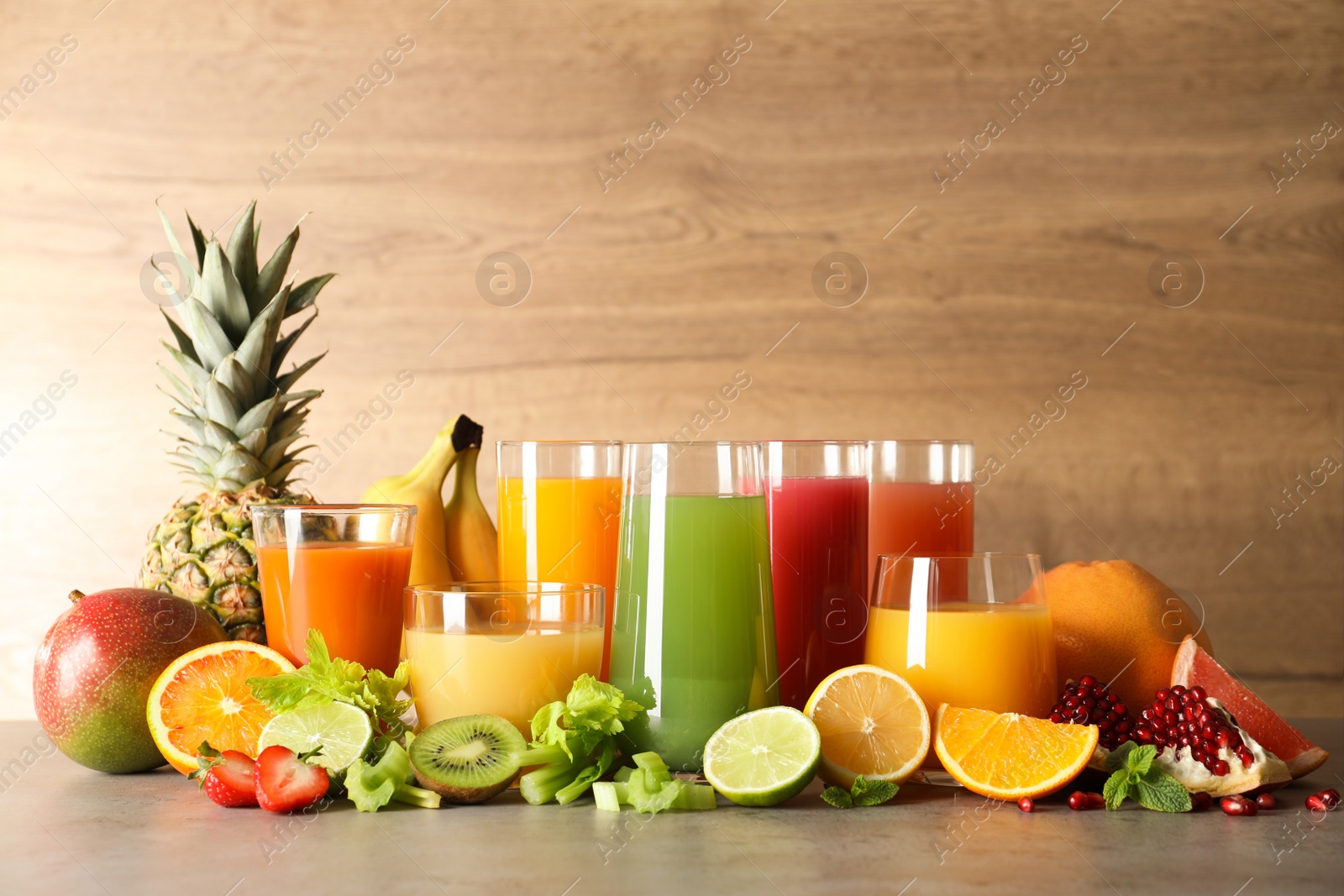 Photo of Glasses with different juices and fresh fruits on table