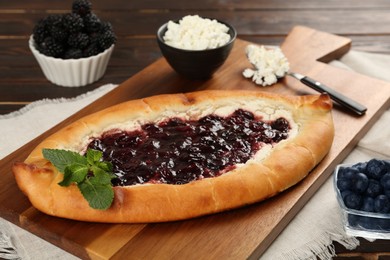 Photo of Delicious sweet cottage cheese pastry with cherry jam served on wooden table