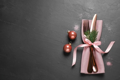 Photo of Cutlery set on black table, top view with space for text. Christmas celebration