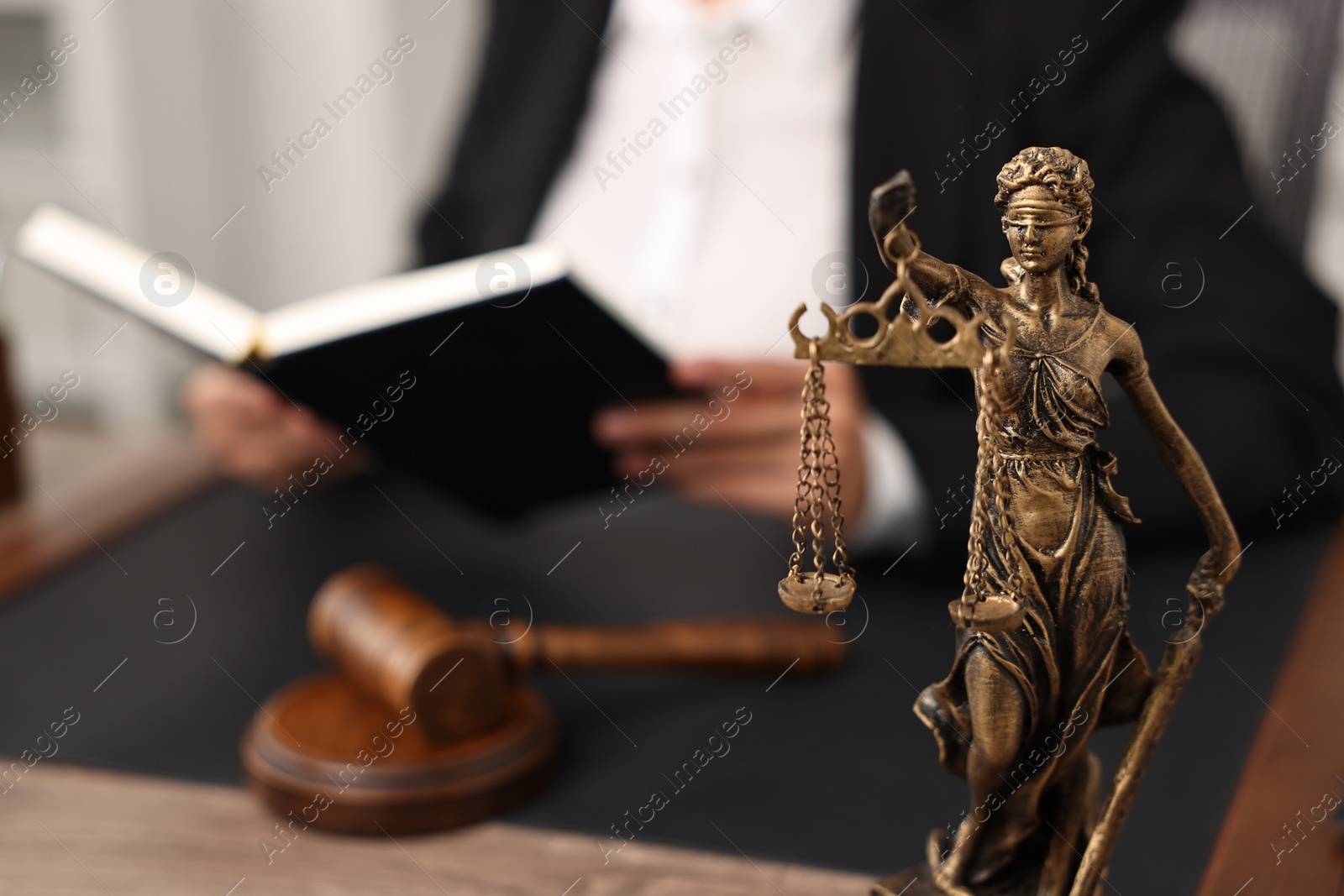 Photo of Notary with notebook at workplace in office, focus on statue of Lady Justice