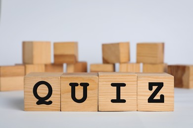 Photo of Wooden cubes with word Quiz on white background. Space for text