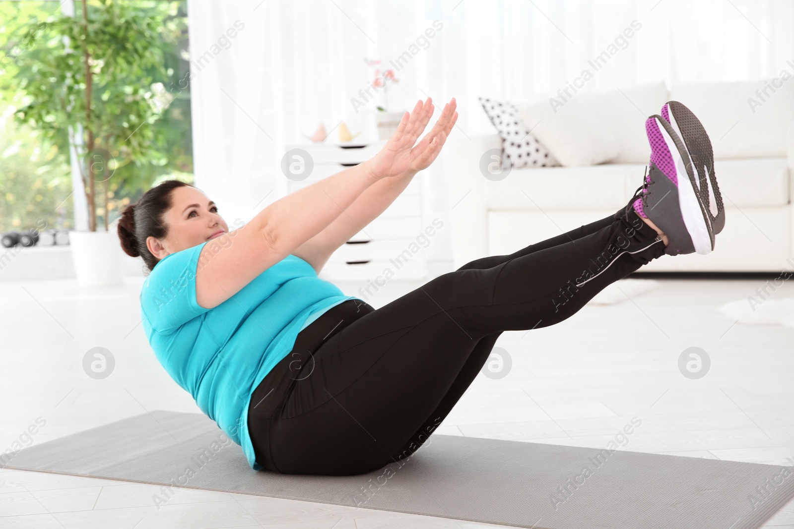 Photo of Overweight woman doing exercise on mat at home