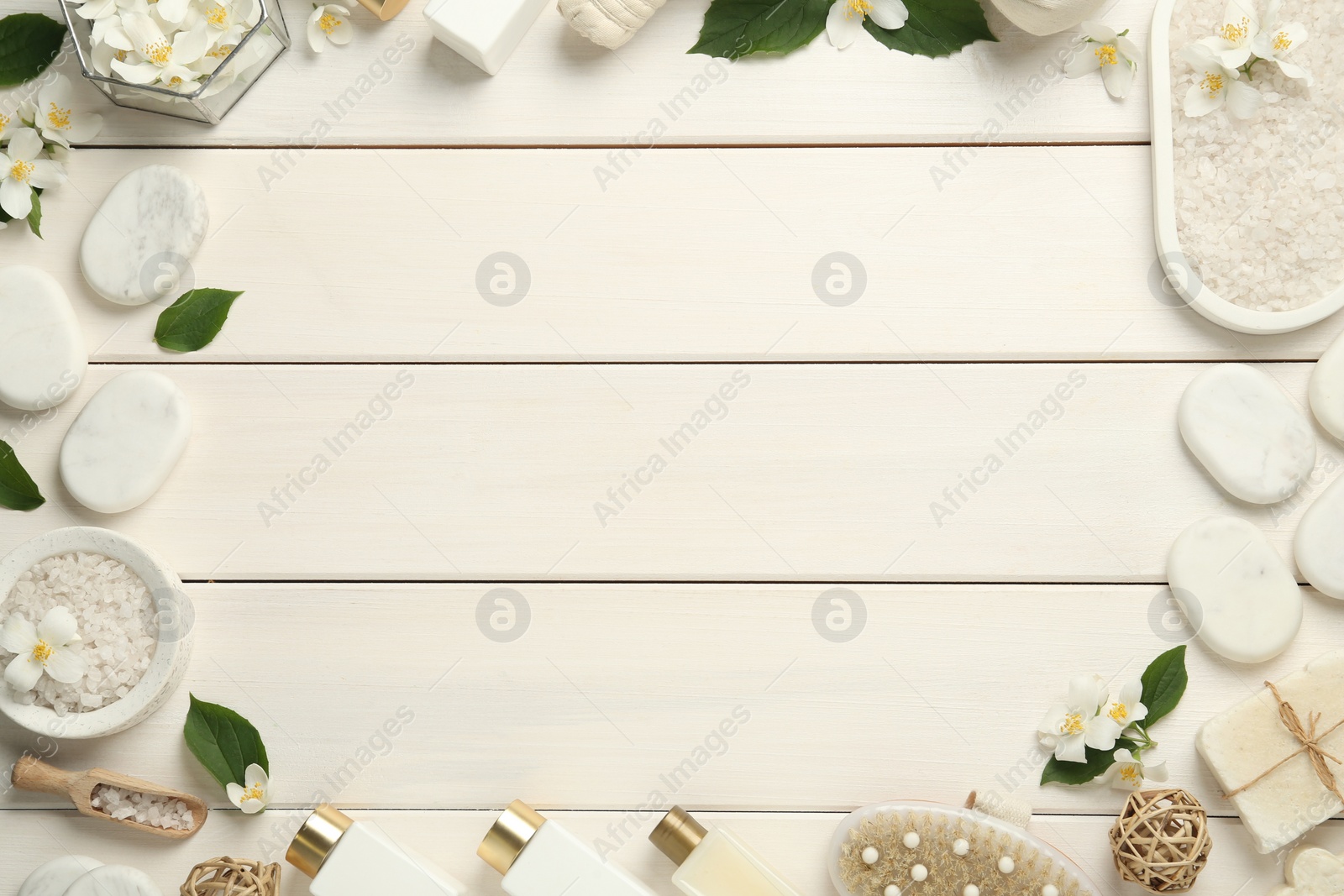 Photo of Jasmine flowers and set of spa essentials on white wooden table, flat lay. Space for text