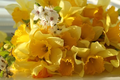 Photo of Yellow daffodils and beautiful white flowers of plum tree on table, closeup