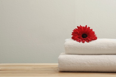 Stack of fresh towels with flower on table. Space for text