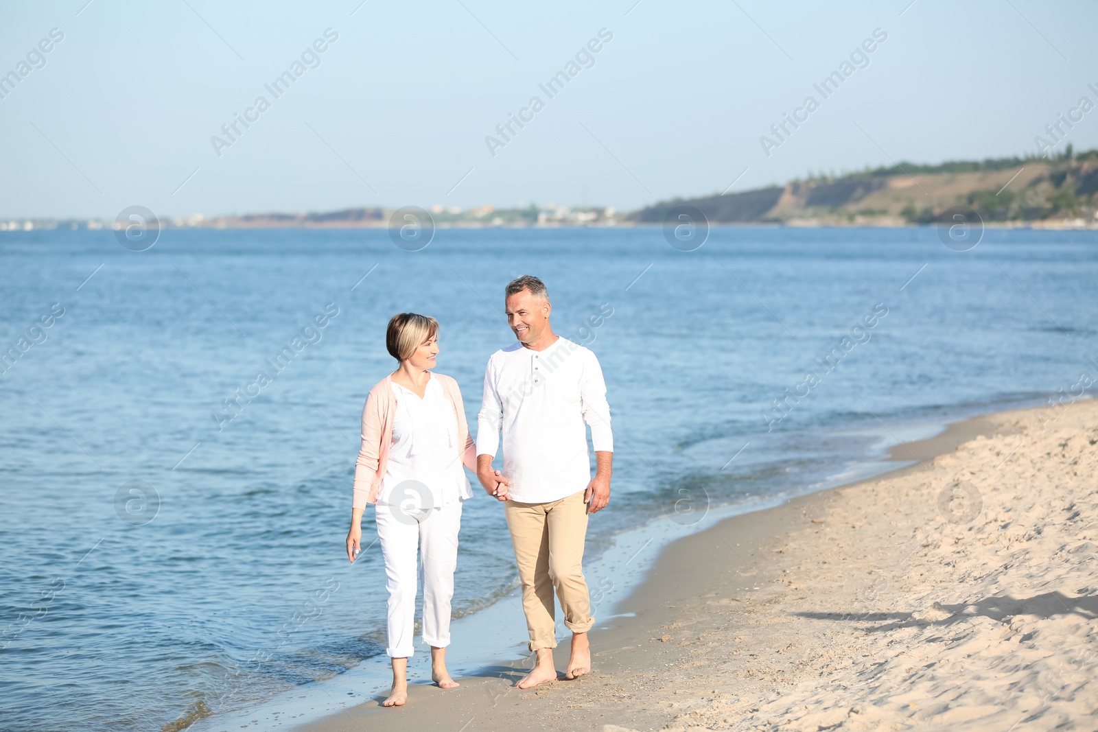 Photo of Happy mature couple walking at beach on sunny day