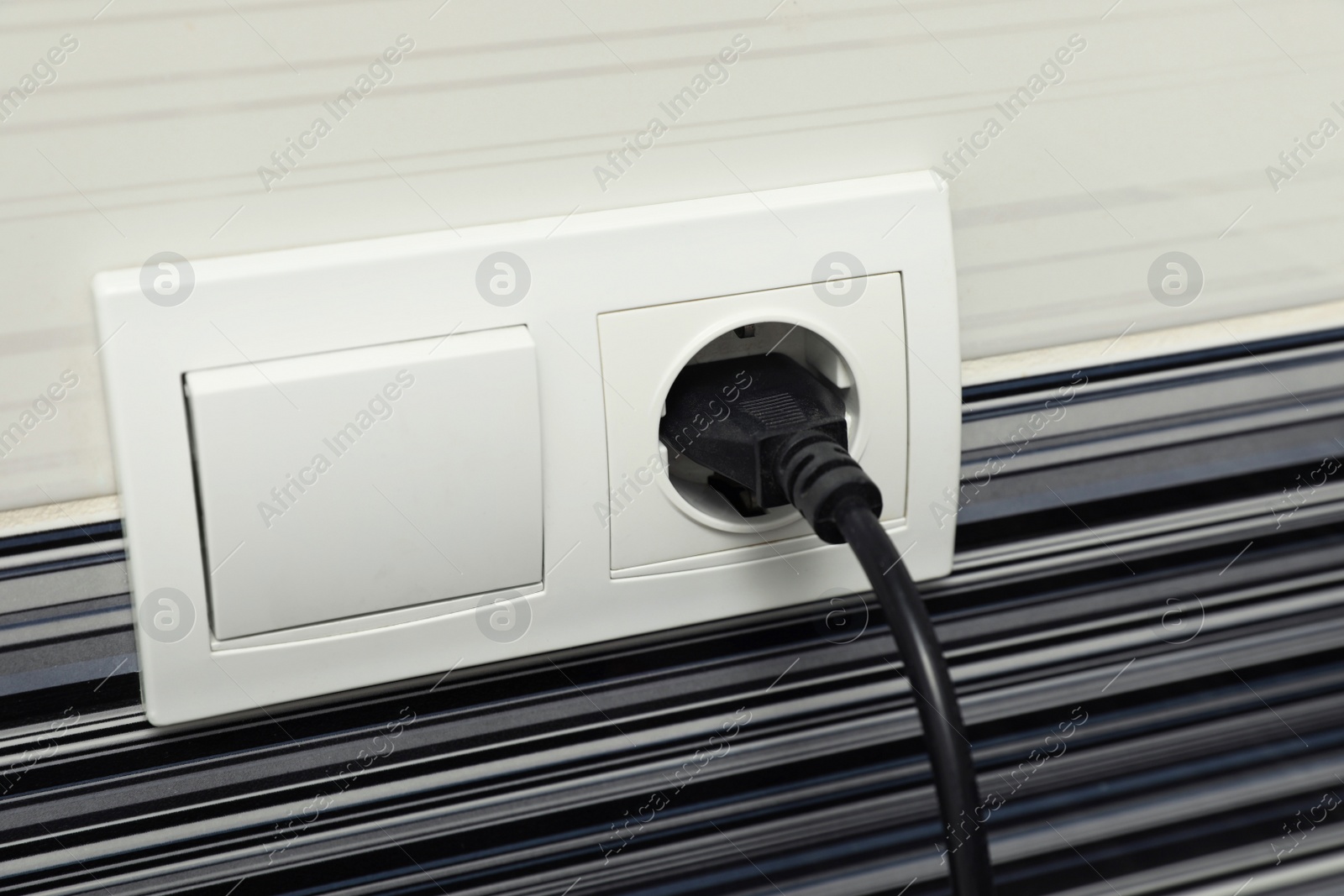 Photo of Power socket and plug on color wall, closeup