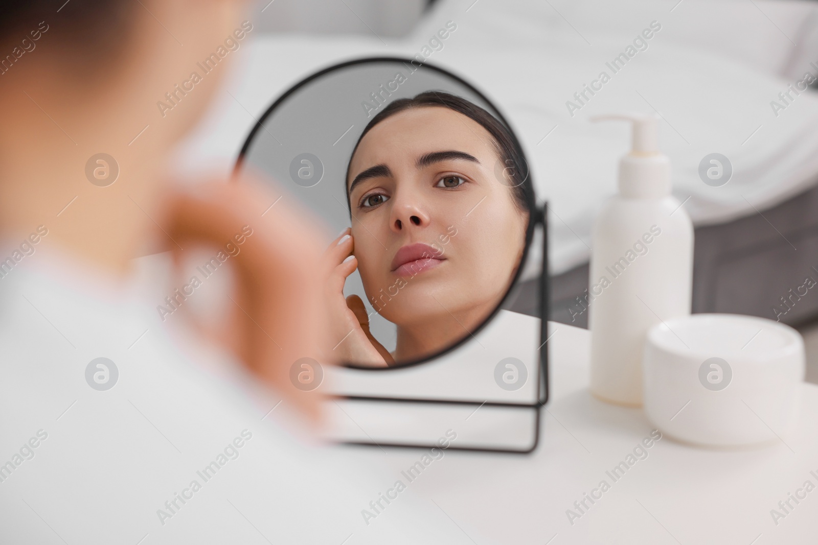 Photo of Woman with dry skin looking at mirror indoors