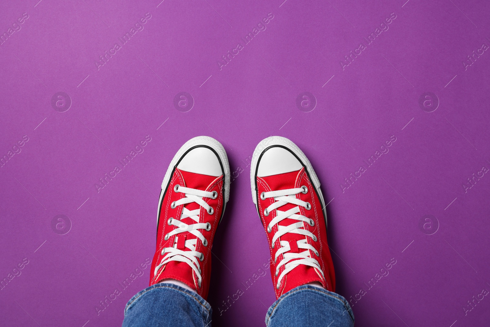 Photo of Woman in stylish gumshoes on purple background, top view