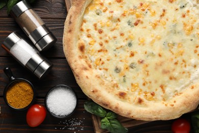 Photo of Delicious cheese pizza and ingredients on wooden table, flat lay