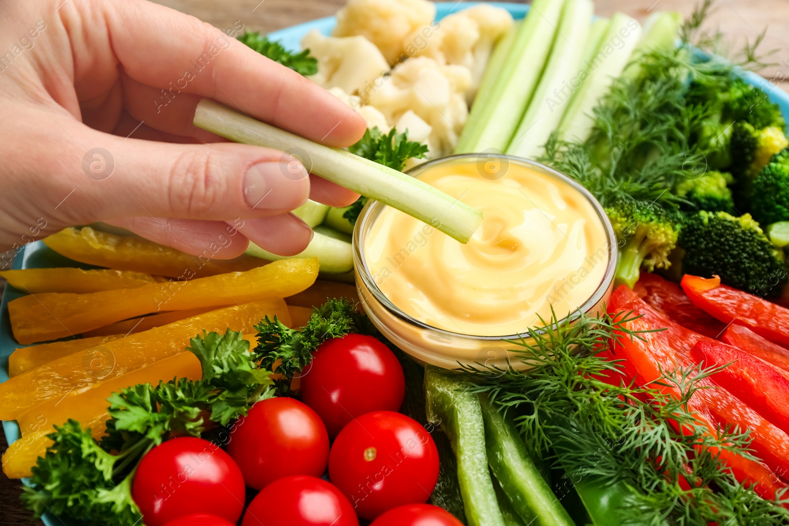 Photo of Woman dipping celery stick in sauce, closeup