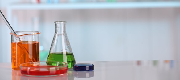 Photo of Laboratory analysis. Different glassware with liquids on white table against blurred background. Space for text