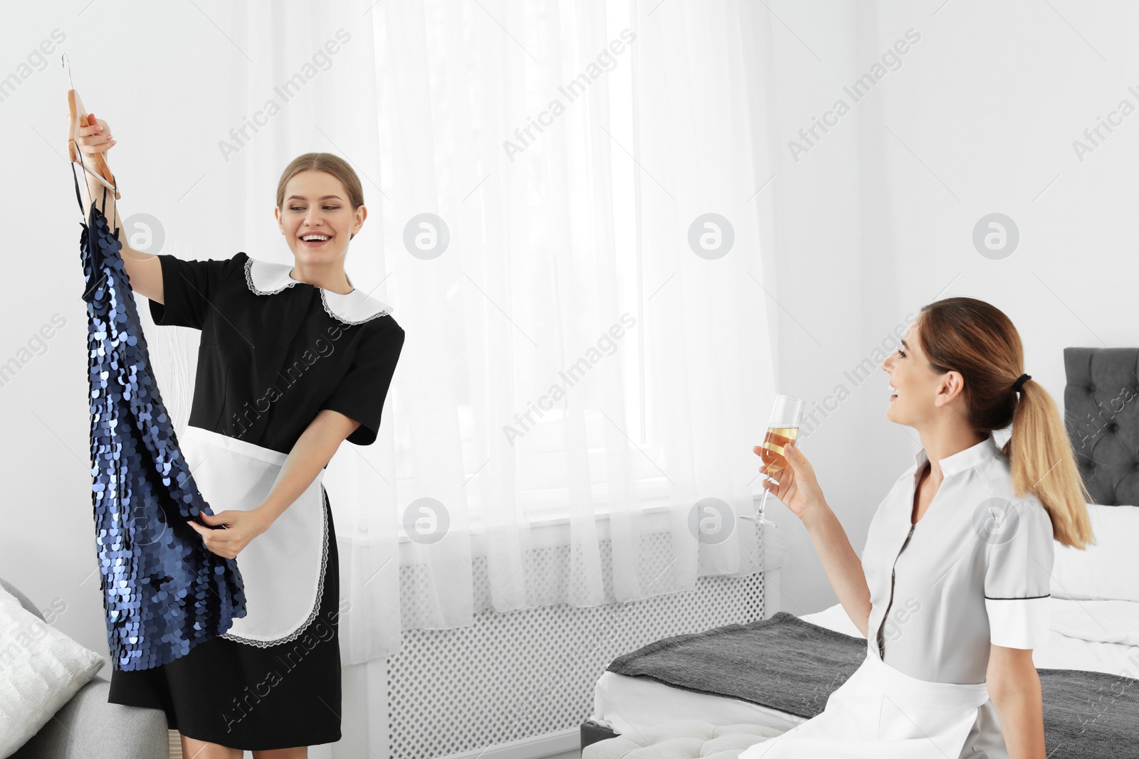 Photo of Young chambermaids trying on clothes in hotel room