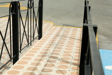 Tiled ramp with black metal railings outdoors