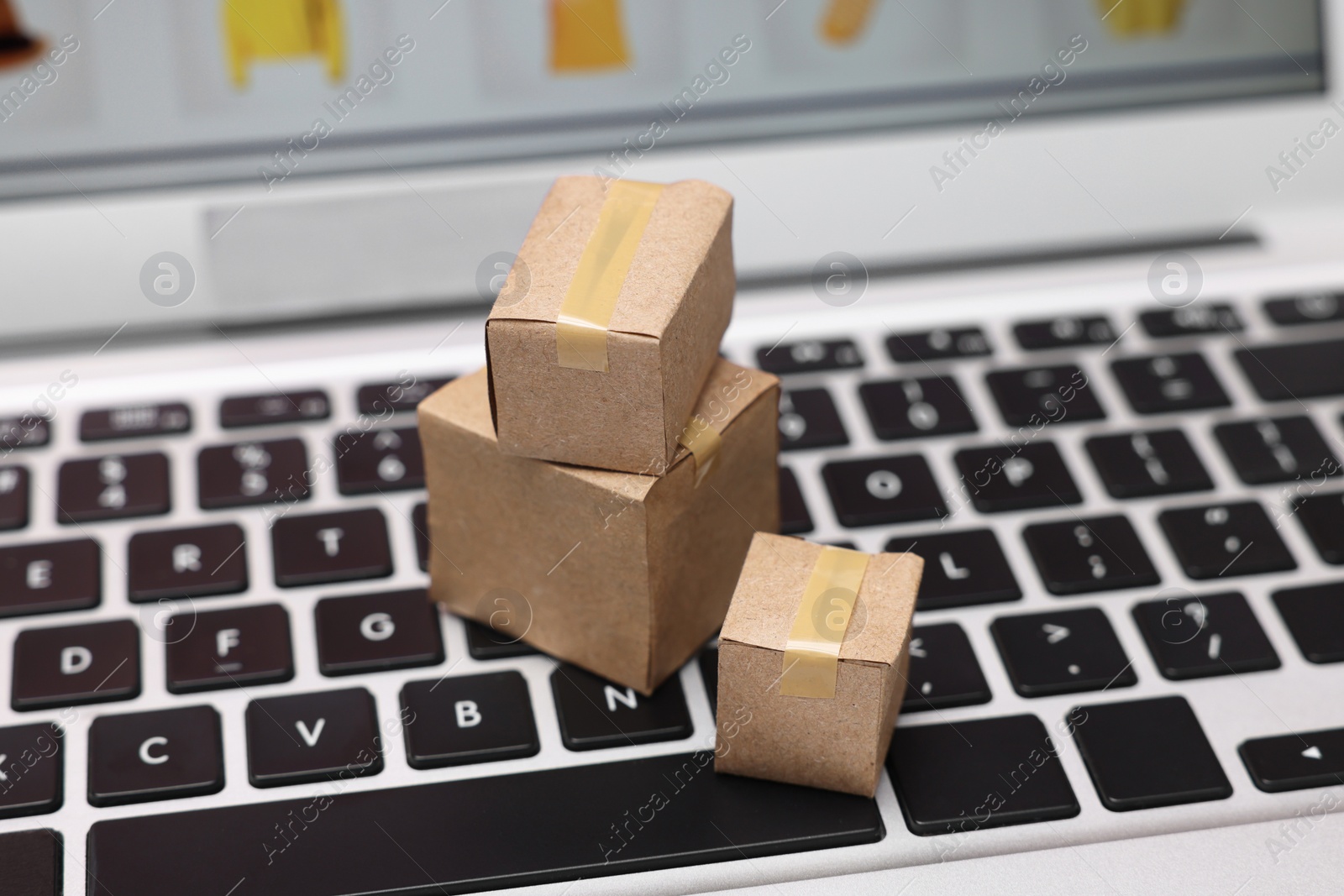 Photo of Internet shopping. Small cardboard boxes on laptop, closeup