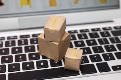 Internet shopping. Small cardboard boxes on laptop, closeup