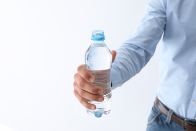 Man holding bottle of pure water on white background, closeup. Space for text