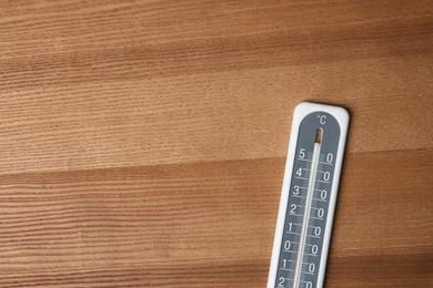 Photo of Weather thermometer on wooden table, top view. Space for text