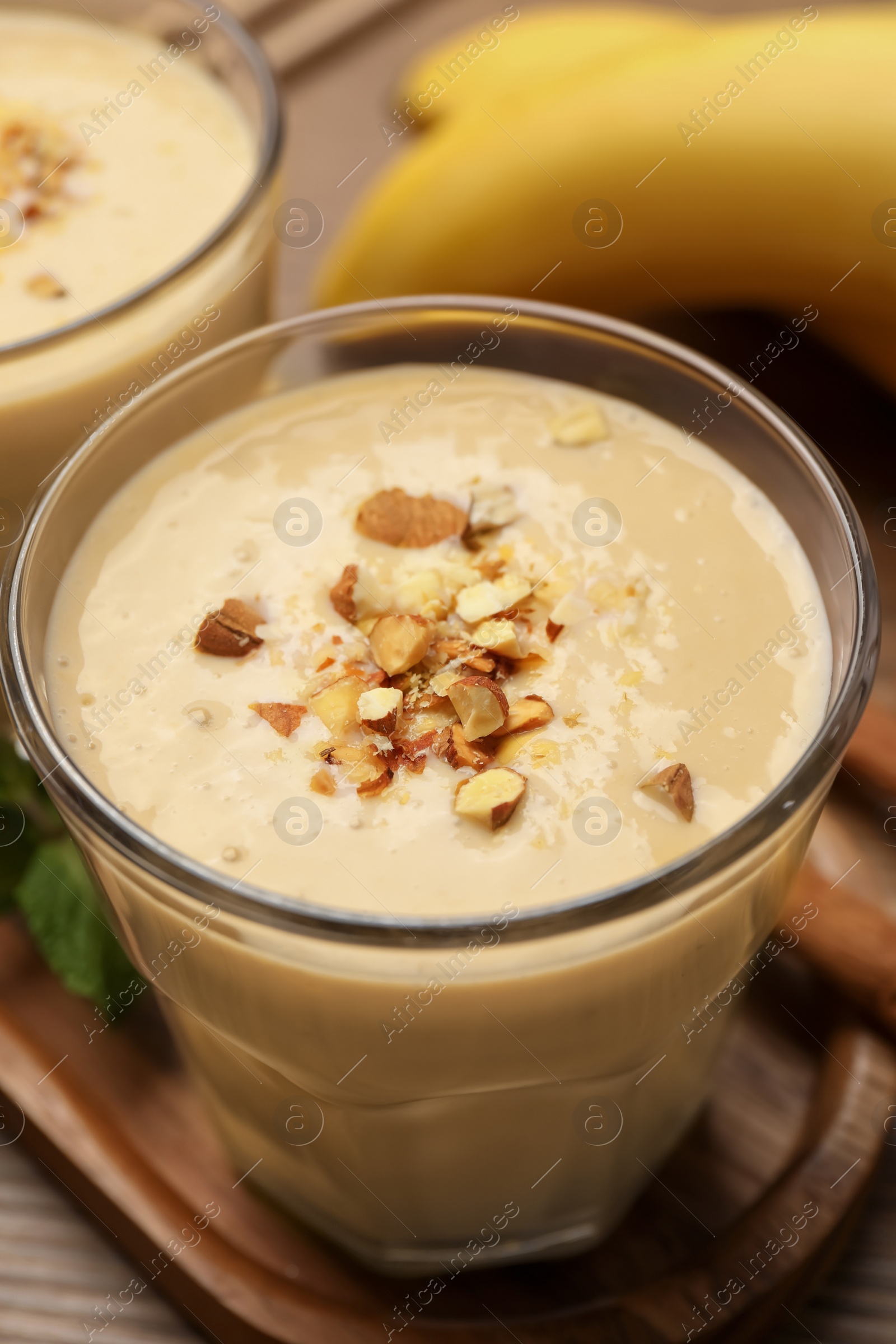 Photo of Tasty banana smoothie with almond and cinnamon on wooden table, closeup