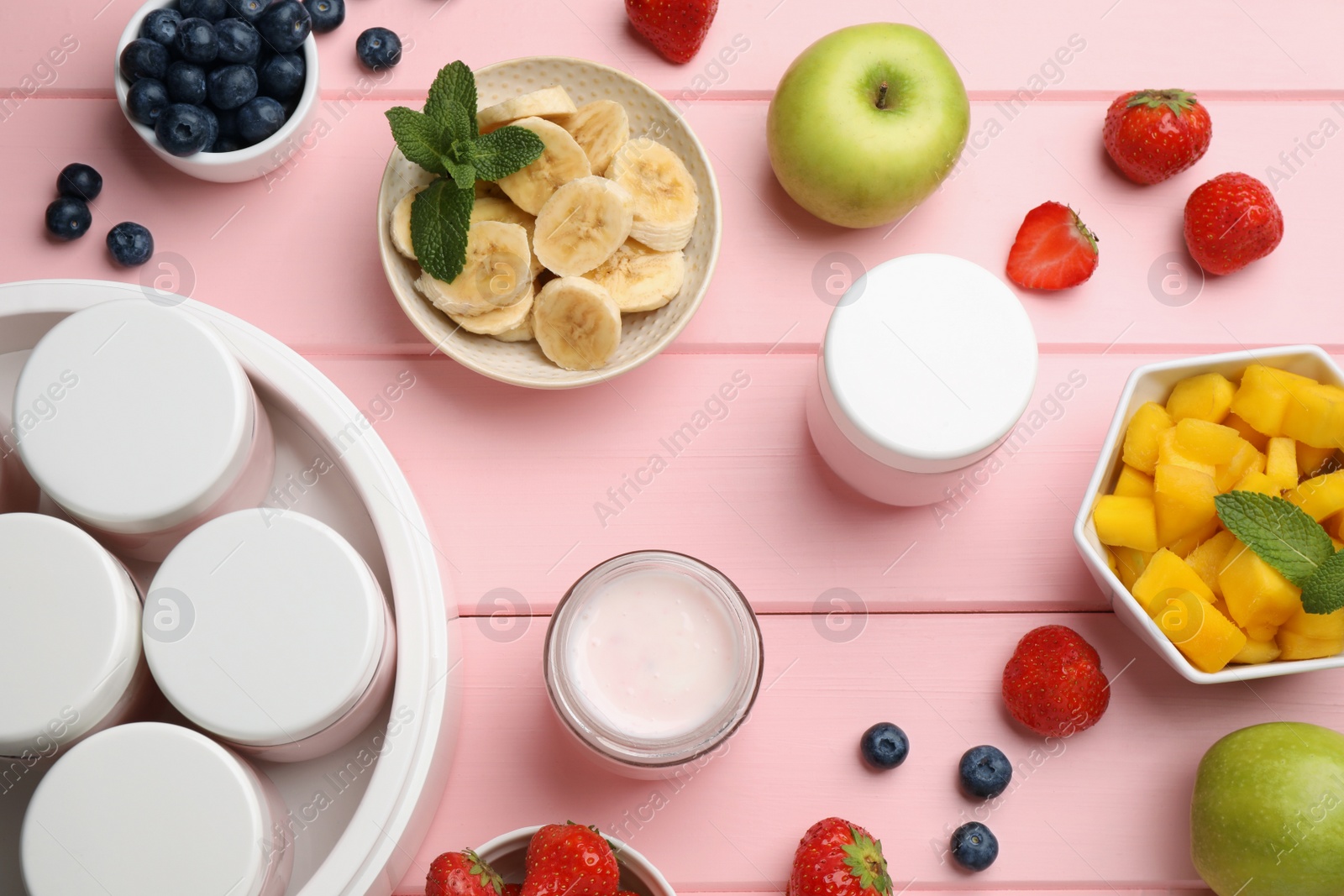 Photo of Modern yogurt maker with full jars and different fruits on pink wooden table, flat lay