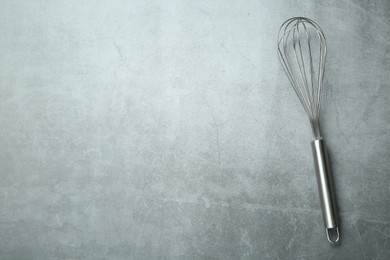 Photo of Metal whisk on gray table, top view. Space for text