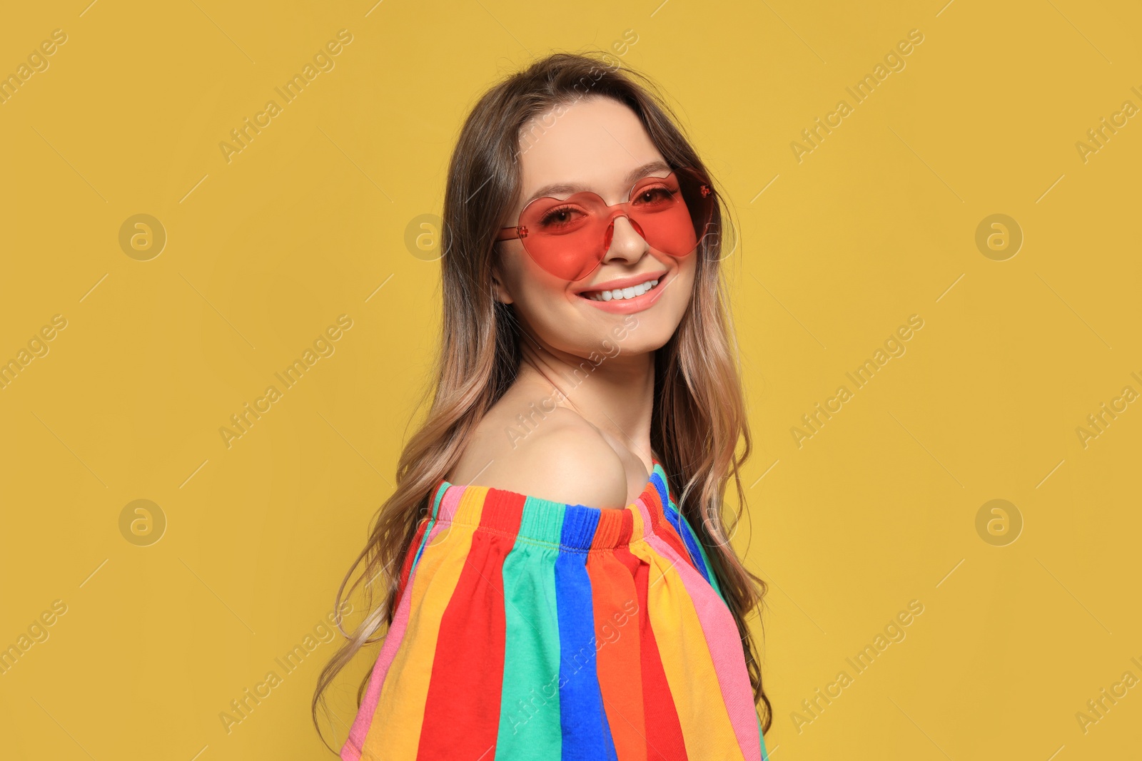 Photo of Portrait of beautiful young woman with heart shaped sunglasses on color background