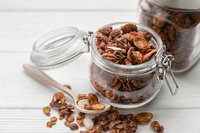 Photo of Jars with tasty granola on white wooden table, closeup