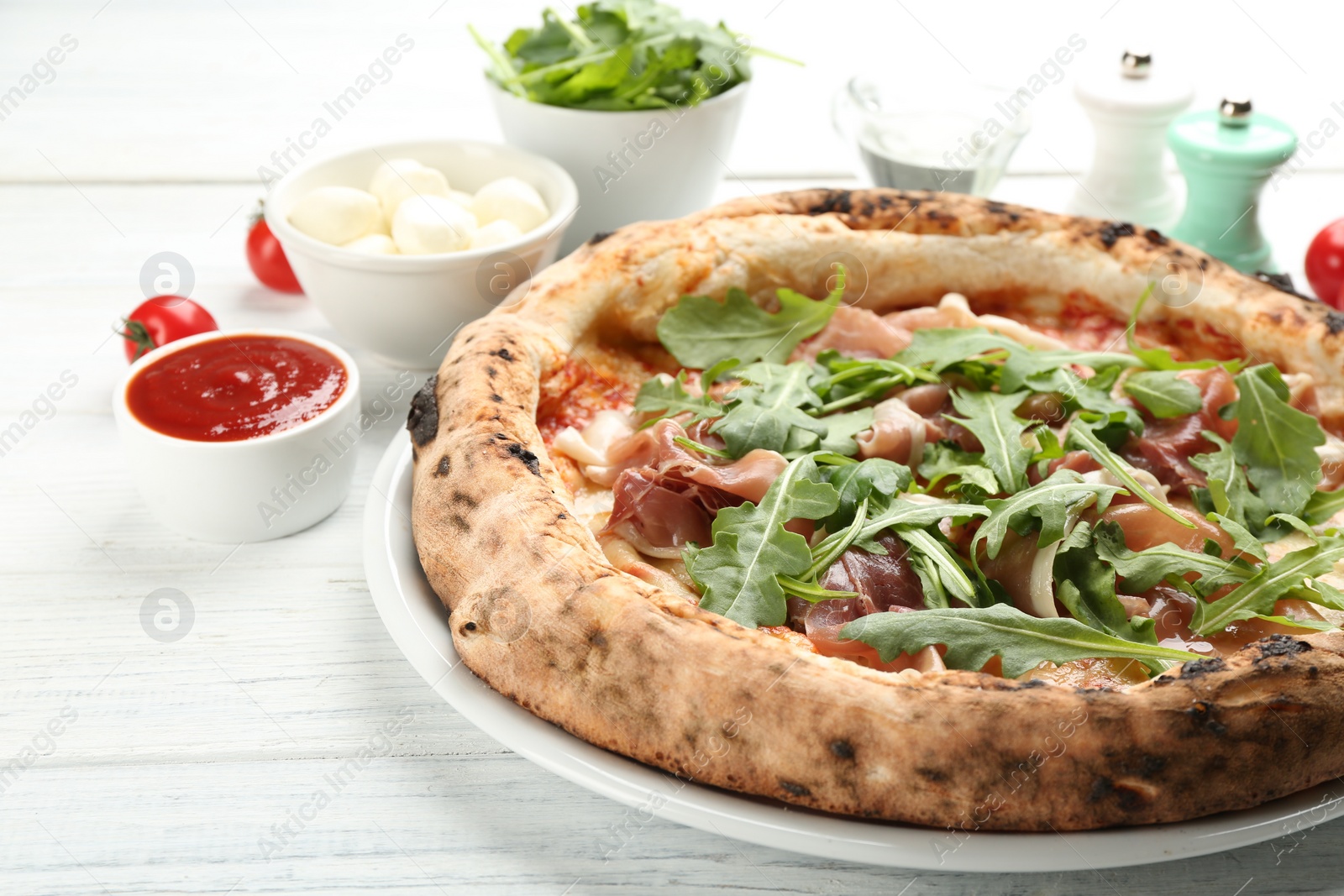 Photo of Tasty pizza with meat and arugula on white wooden table, closeup