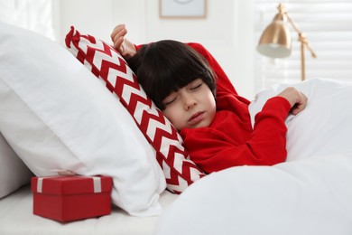 Photo of Cute little boy sleeping in bed, gift box under pillow. Saint Nicholas day tradition