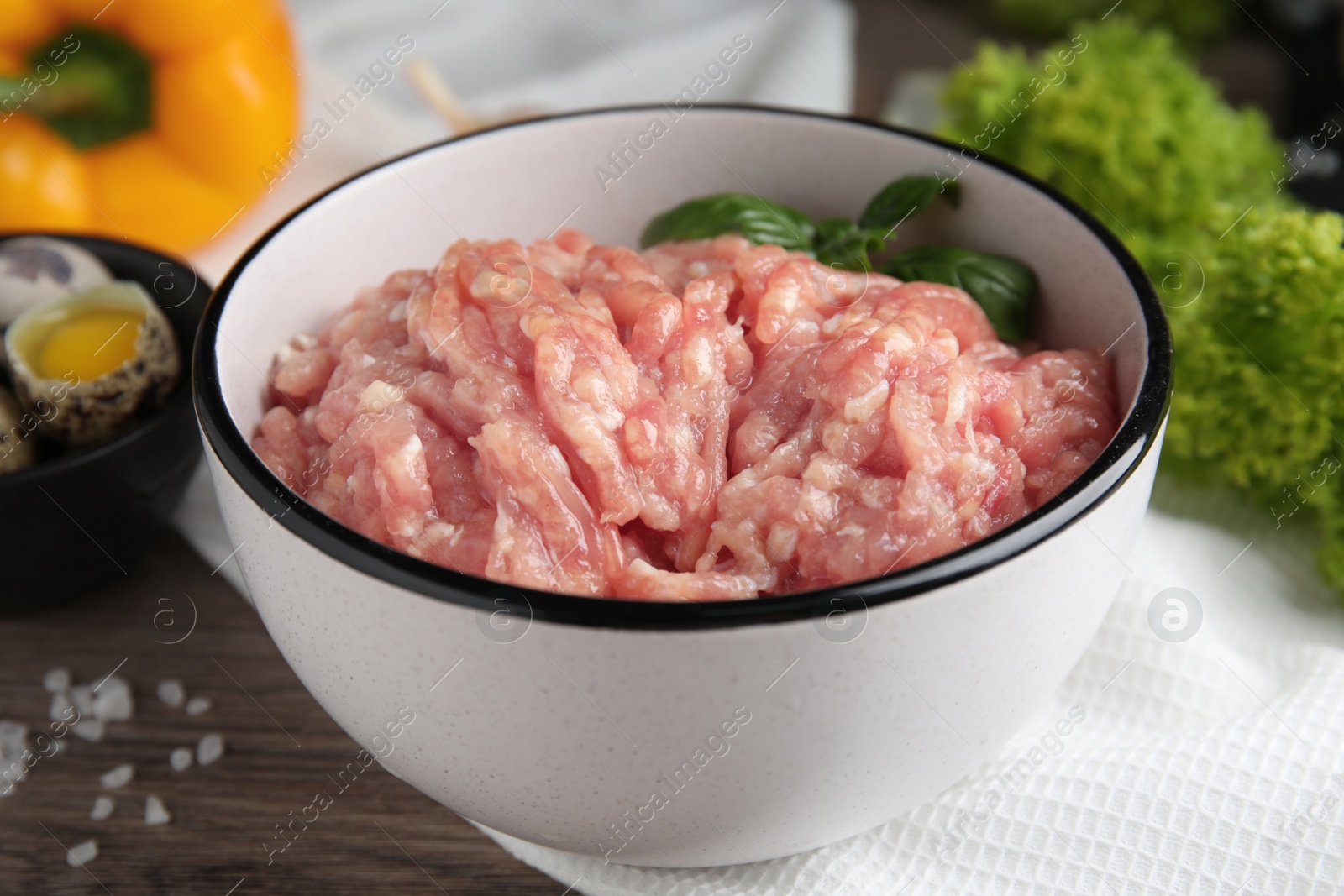 Photo of Raw chicken minced meat with basil on wooden table, closeup