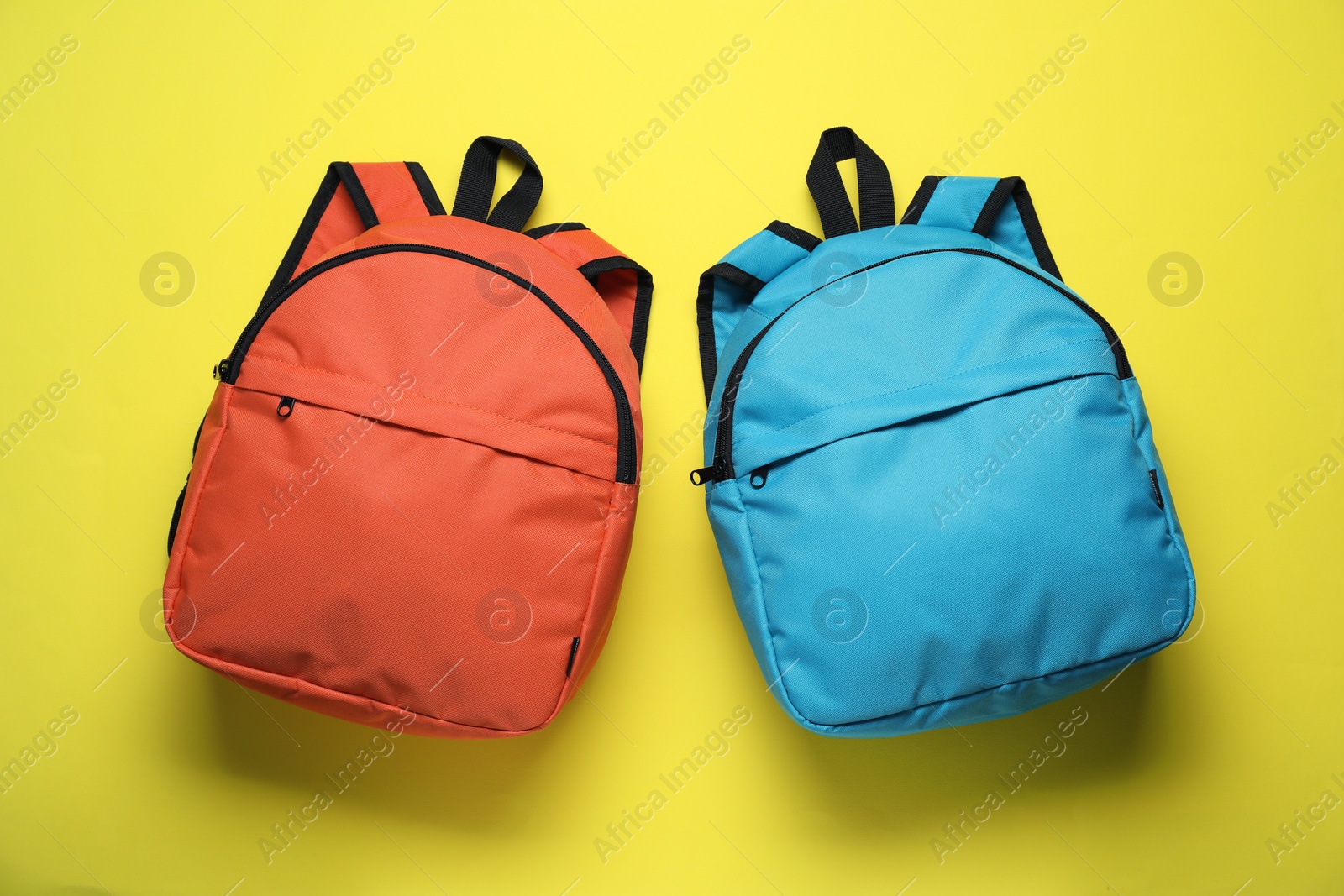 Photo of Stylish backpacks on yellow background, flat lay