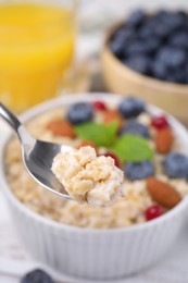 Spoon of oatmeal at table, closeup view