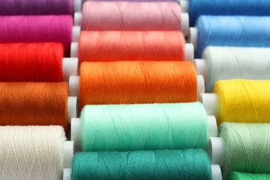 Photo of Set of different colorful sewing threads as background, closeup