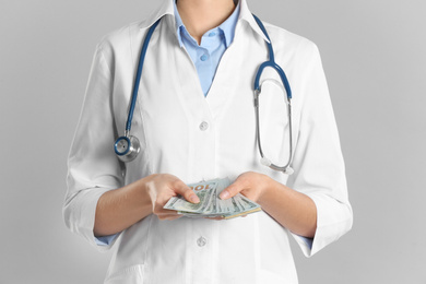 Photo of Doctor with bribe on grey background, closeup. Corruption in medicine