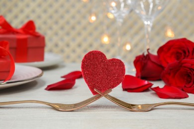 Photo of Forks and decorative heart on white table. Romantic place setting