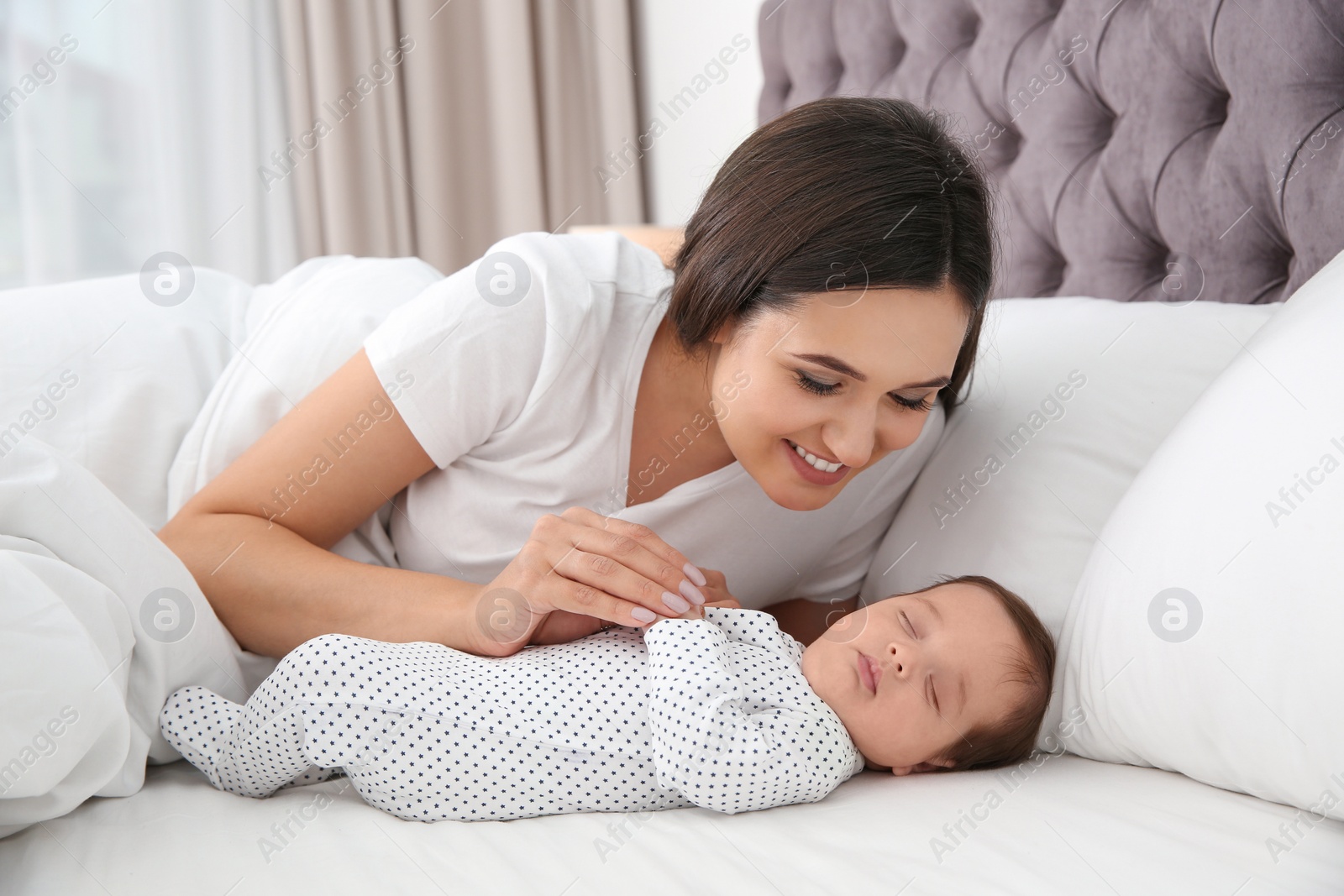 Photo of Happy woman with her sleeping baby on bed