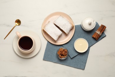 Delicious strudel with powdered sugar served on white marble table, flat lay