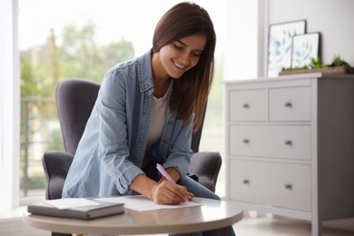 Photo of Woman writing paper letter at table indoors