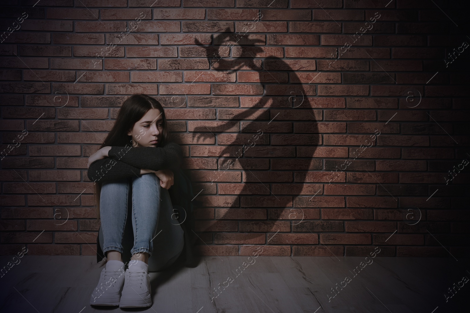 Image of Shadow of monster on wall and scared teenage girl in room