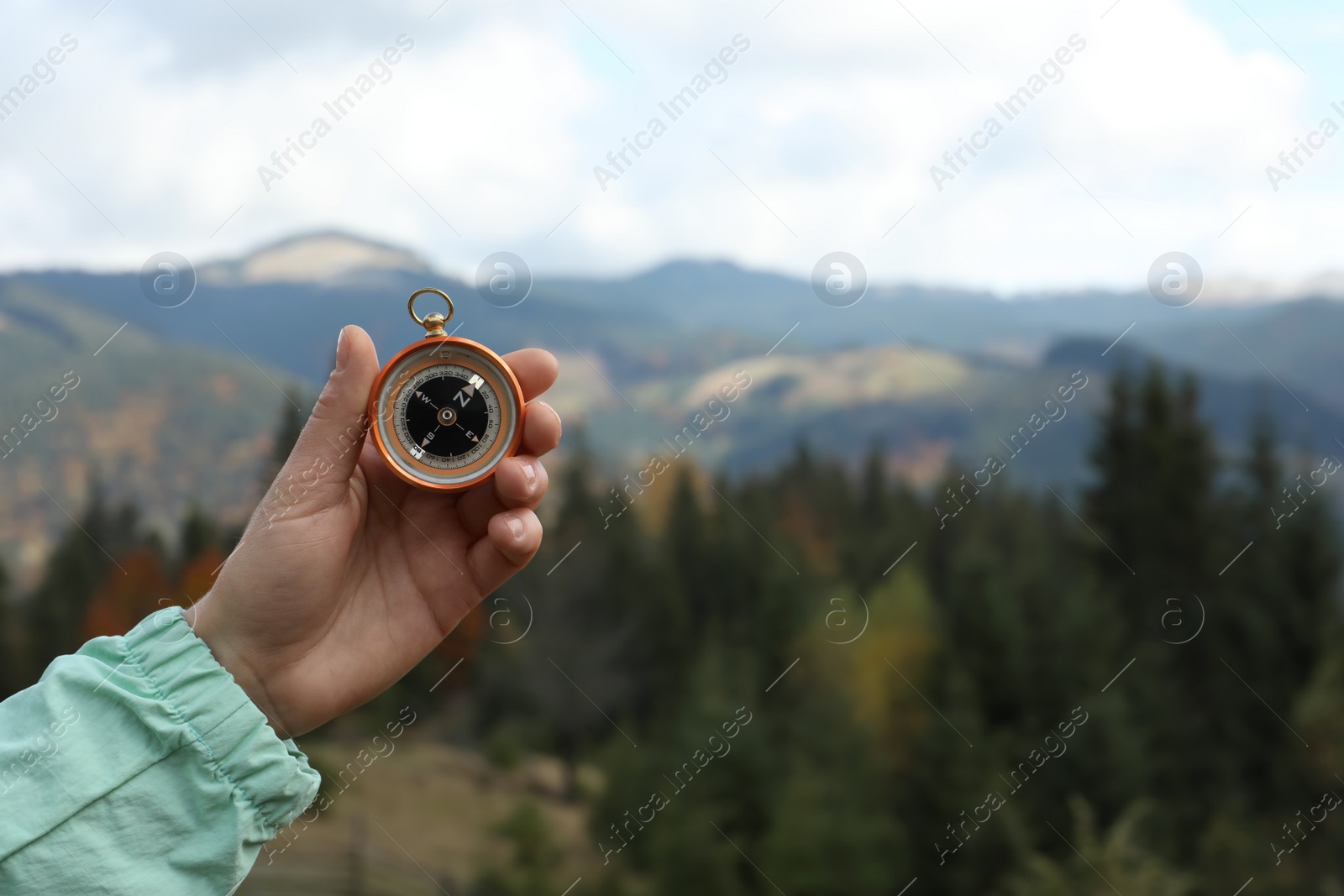 Photo of Woman using compass during journey in mountains, closeup