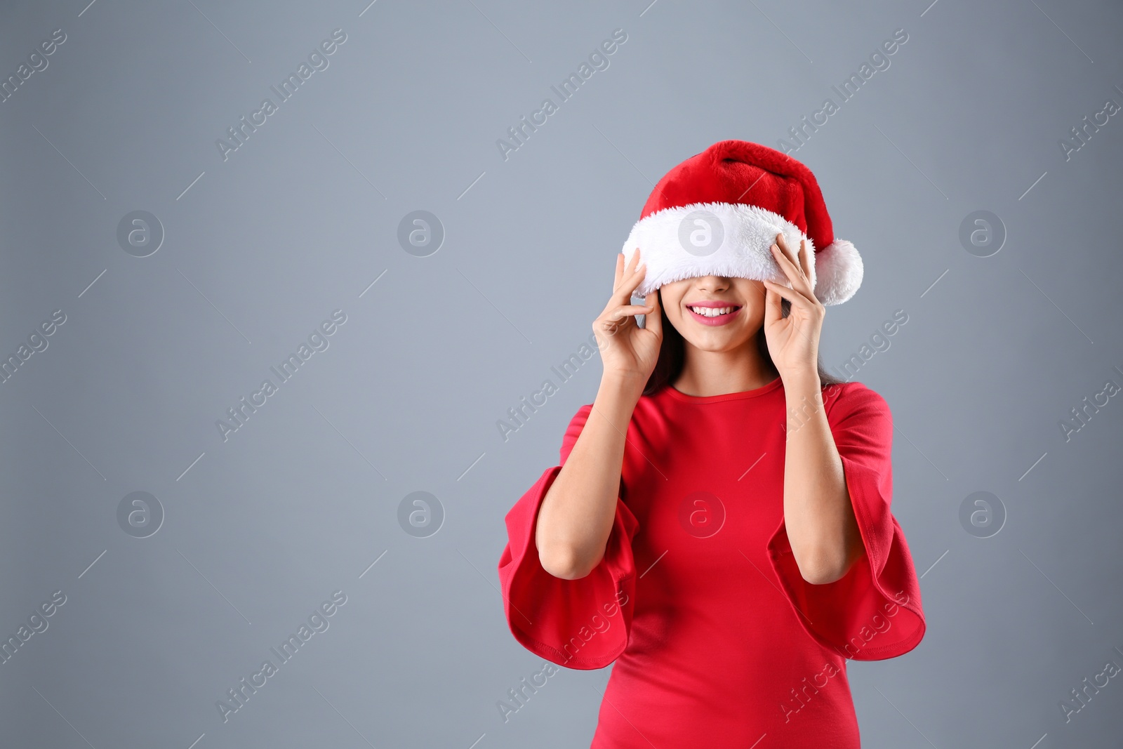 Photo of Young beautiful woman in Santa hat on grey background. Christmas celebration