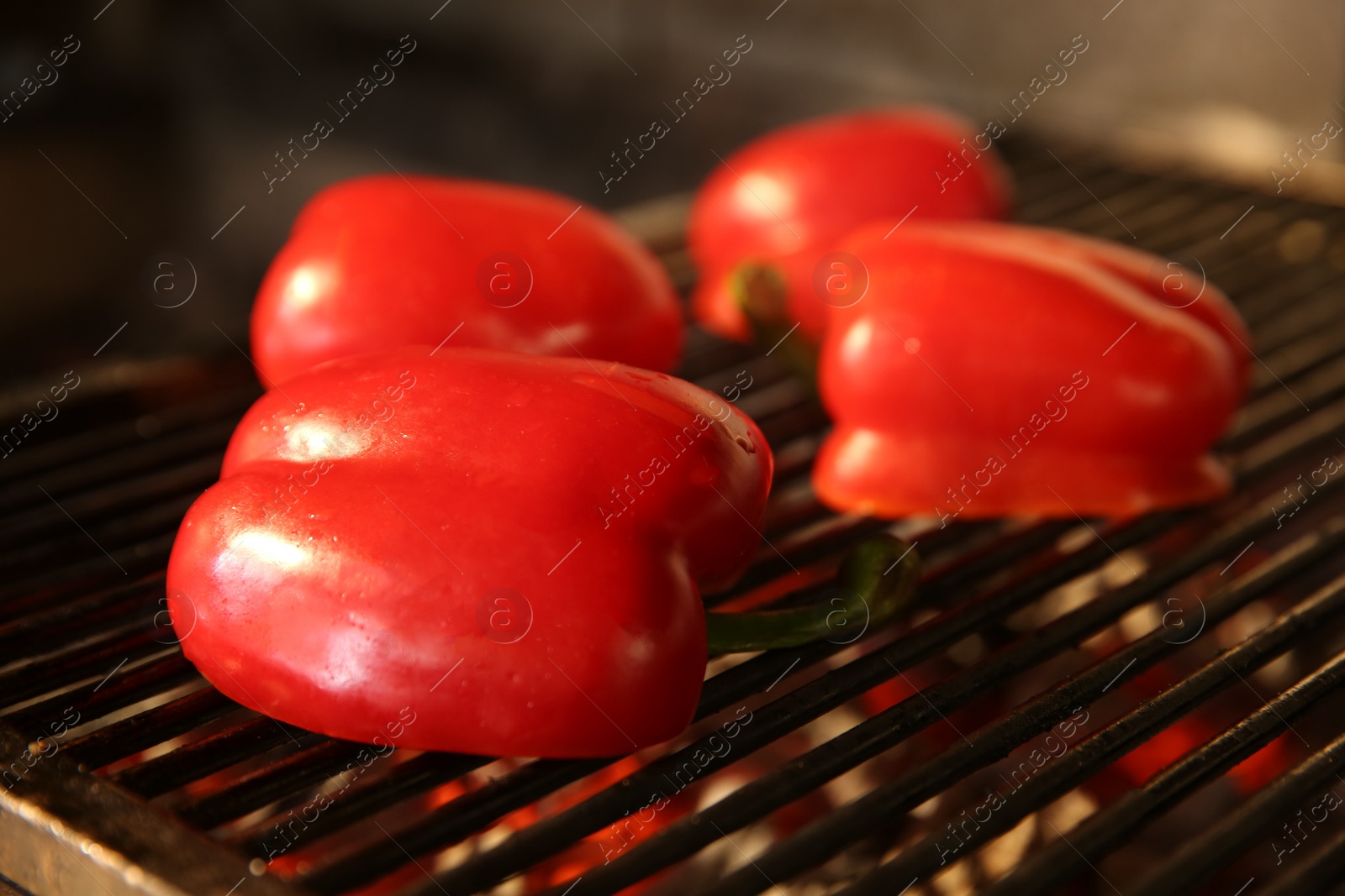 Photo of Cooking delicious fresh bell peppers on grilling grate in oven, closeup
