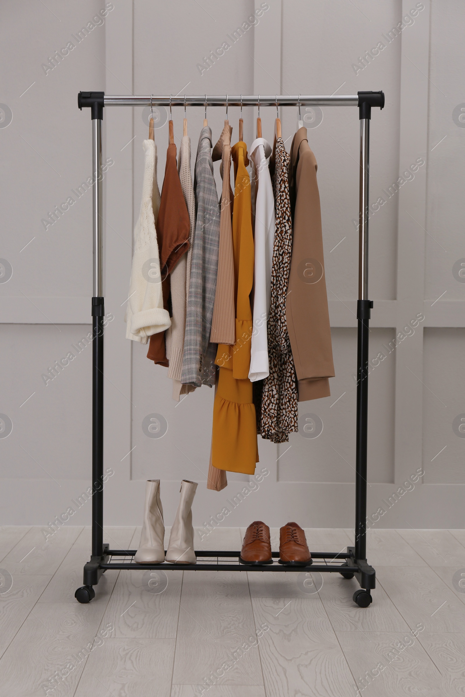 Photo of Rack with different stylish clothes near grey wall indoors