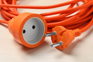 Photo of Extension cord on white wooden floor, closeup. Electrician's equipment