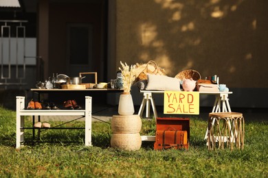 Table with different stuff and sign Yard sale outdoors