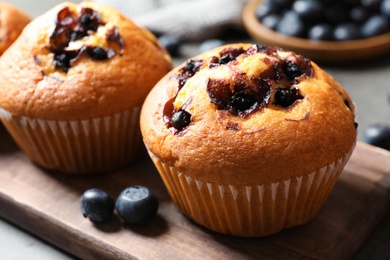 Photo of Tasty blueberry muffins on wooden board, closeup view