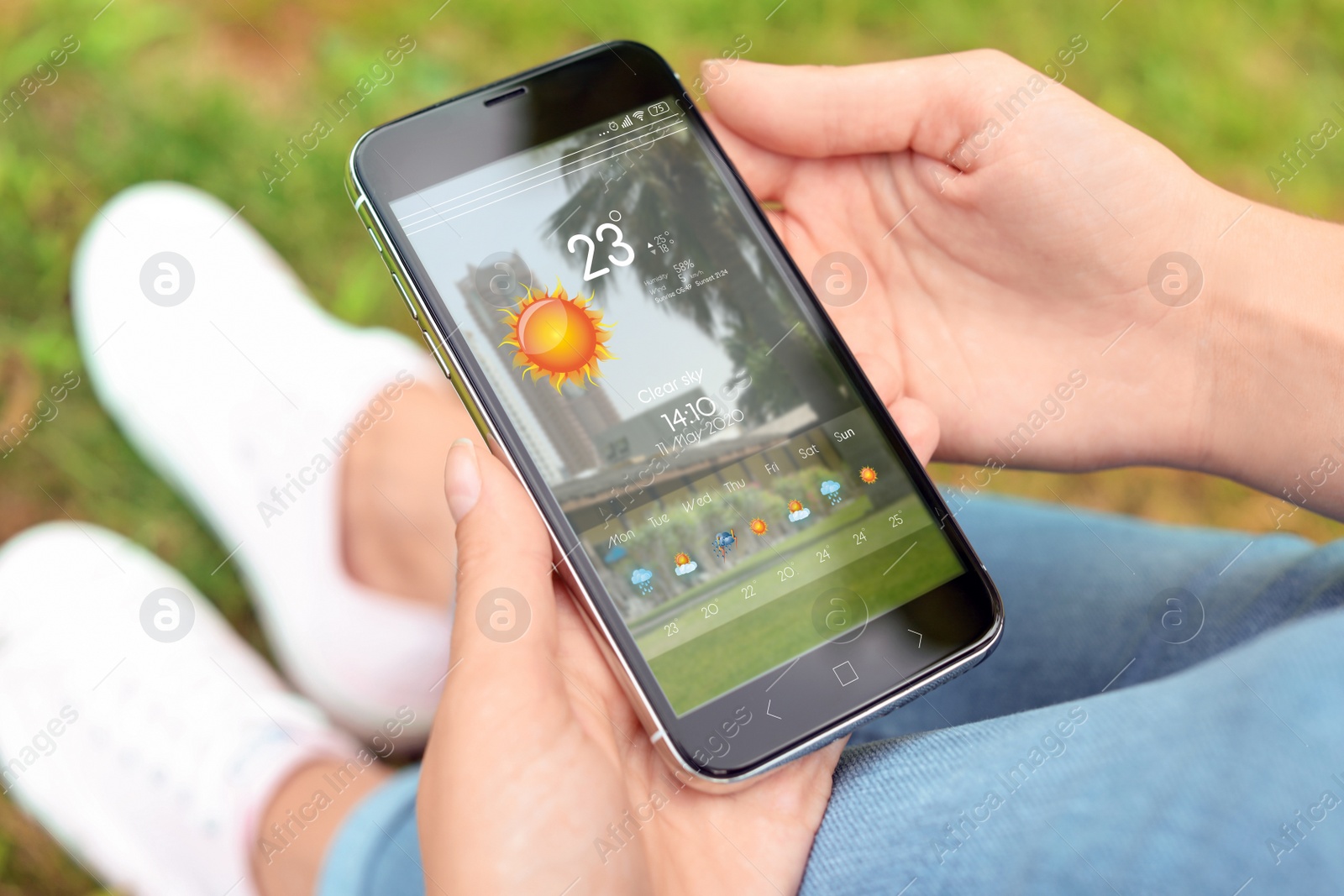 Image of Woman using weather forecast app on smartphone outdoors, closeup